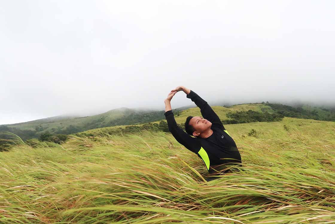 Man Stretching In Grassy Field from Hemp Oil Pain Relief Article