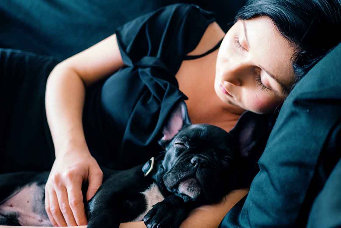 Woman Sleeping with Pug from Article on Natural Ways to Fall and Stay Asleep